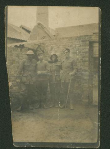 Faded sepia photograph of four men in uniform.