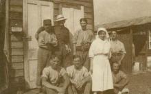 Sepia photograph of eight people, featuring Alice Thompson in nurse uniform
