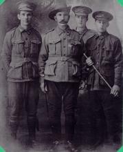 Black and white portrait of four men in uniform.