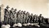 Sepia photograph of soldiers in uniform standing in a line.